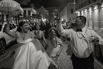 newlyweds and guests walk down new orleans street for their wedding parade