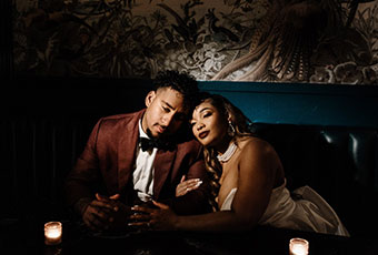 bride and groom lean into each other while sitting in booth at Peacock Room at Kimpton Hotel Fontenot